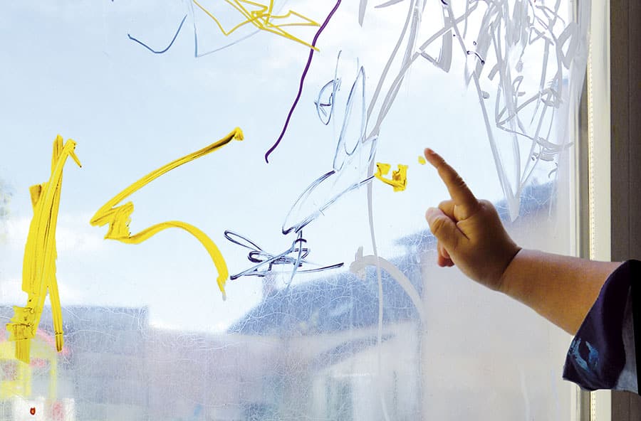 Enfant peint sur vitre avec son doigt